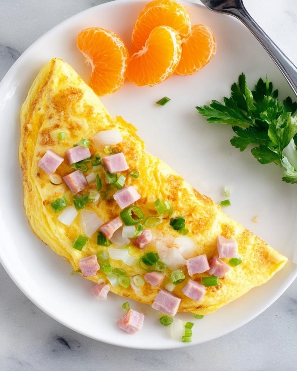 A white plate with a folded yellow omelet topped evenly with small pieces of diced green bell pepper, white onion, and pink ham scattered on the top surface; to the left of the omelet, there are two semicircles of bright orange mandarin segments laid neatly, and above them, a small bunch of fresh green cilantro leaves. A silver fork rests on the left edge of the plate, placed on a white marbled surface. The photo is taken with an iphone --ar 4:5 --v 7
