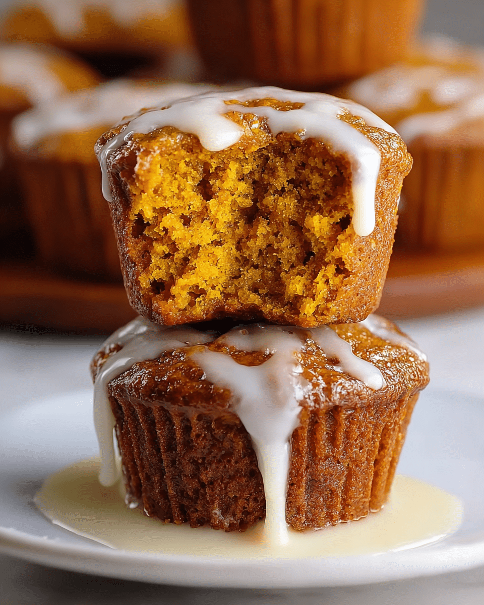 A group of golden brown muffins with a rough, crumbly texture are shown on a white tray, each muffin topped with thin, white icing drizzled in irregular lines. The muffins are closely packed, with the closest one sharply in focus, showing a detailed cracked top and moist crumbs. The background is blurred, with soft natural light coming through a window, and the setting is a white marbled surface. photo taken with an iphone --ar 4:5 --v 7