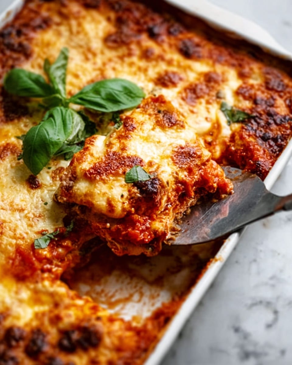 A white speckled plate holds a single slice of lasagna with three distinct layers: a bottom layer of rich, brown meat sauce mixed with tomato, a middle layer of soft, light beige pasta sheets, and a top layer of golden, melted cheese with small browned spots and a sprinkle of green herbs. A fork with a chunk of lasagna is slightly lifting from the plate, showing creamy texture inside. The background features a soft white marbled surface, and a woman's hand is gently holding the fork. Photo taken with an iphone --ar 4:5 --v 7