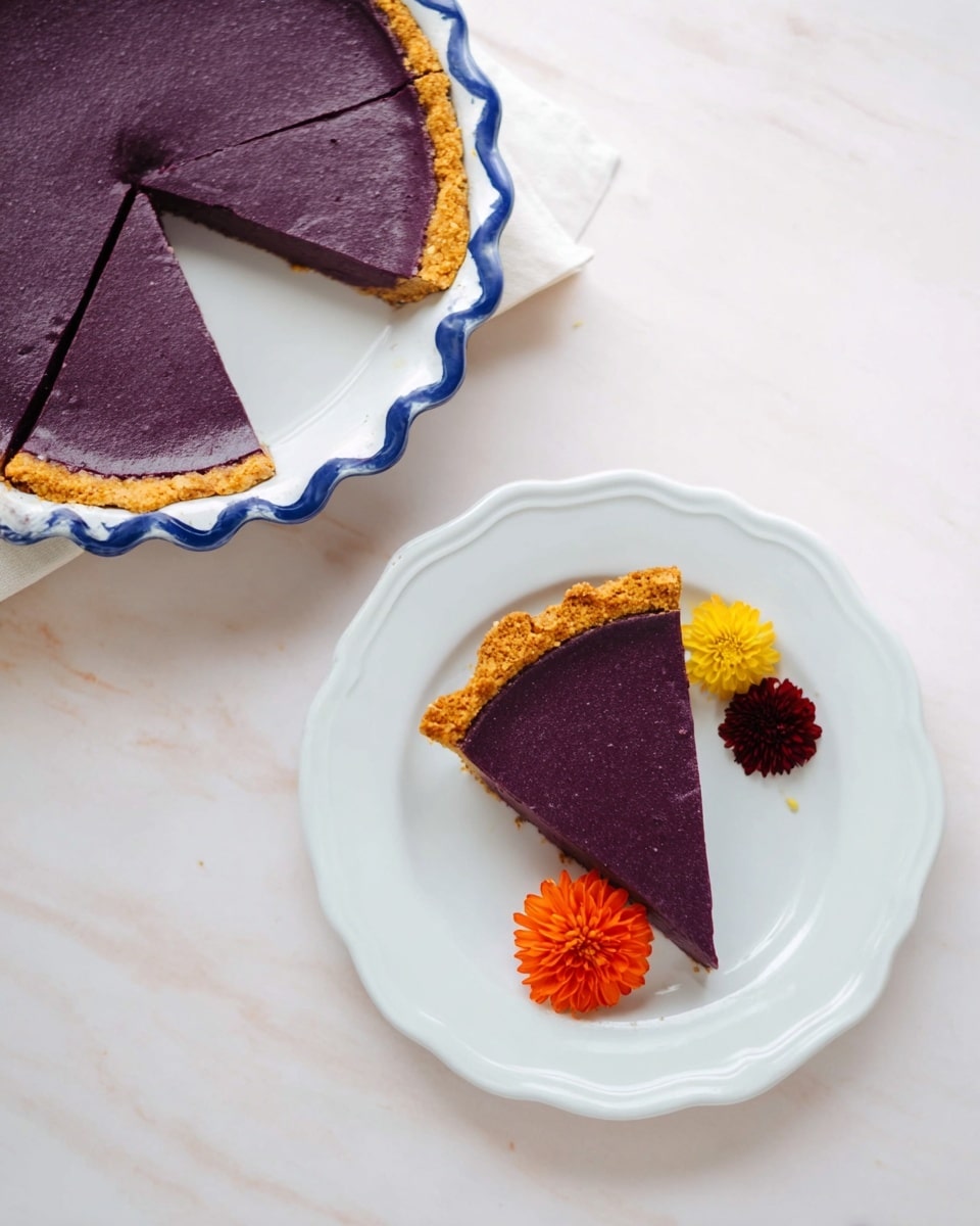 A round pie with one layer of deep purple filling, smooth and glossy, sitting in a white ceramic pie dish with blue scalloped edges and handles, surrounded by a light golden brown crust that is slightly raised and ridged at the edges, decorated with a small cluster of edible yellow, orange, and purple flowers placed on one side near the crust, all set on a white marbled surface photo taken with an iphone --ar 4:5 --v 7