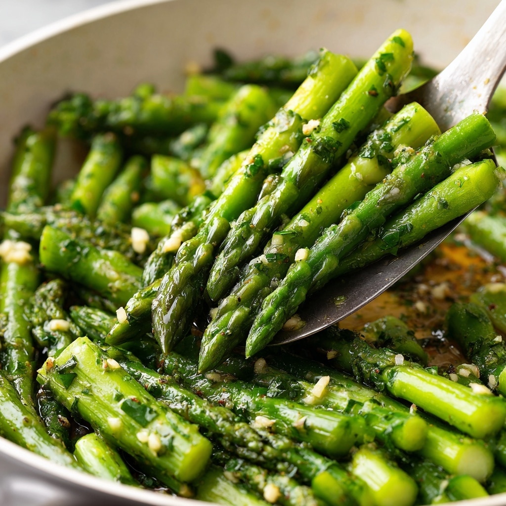 A close-up view of bright green asparagus pieces cooked in a white pan, cut into short segments showing a mix of tender tips and thicker stems all coated with tiny bits of minced garlic and herbs scattered evenly on top, giving a fresh and slightly glossy texture under soft light, the white marbled surface faintly visible in the background, photo taken with an iphone --ar 4:5 --v 7