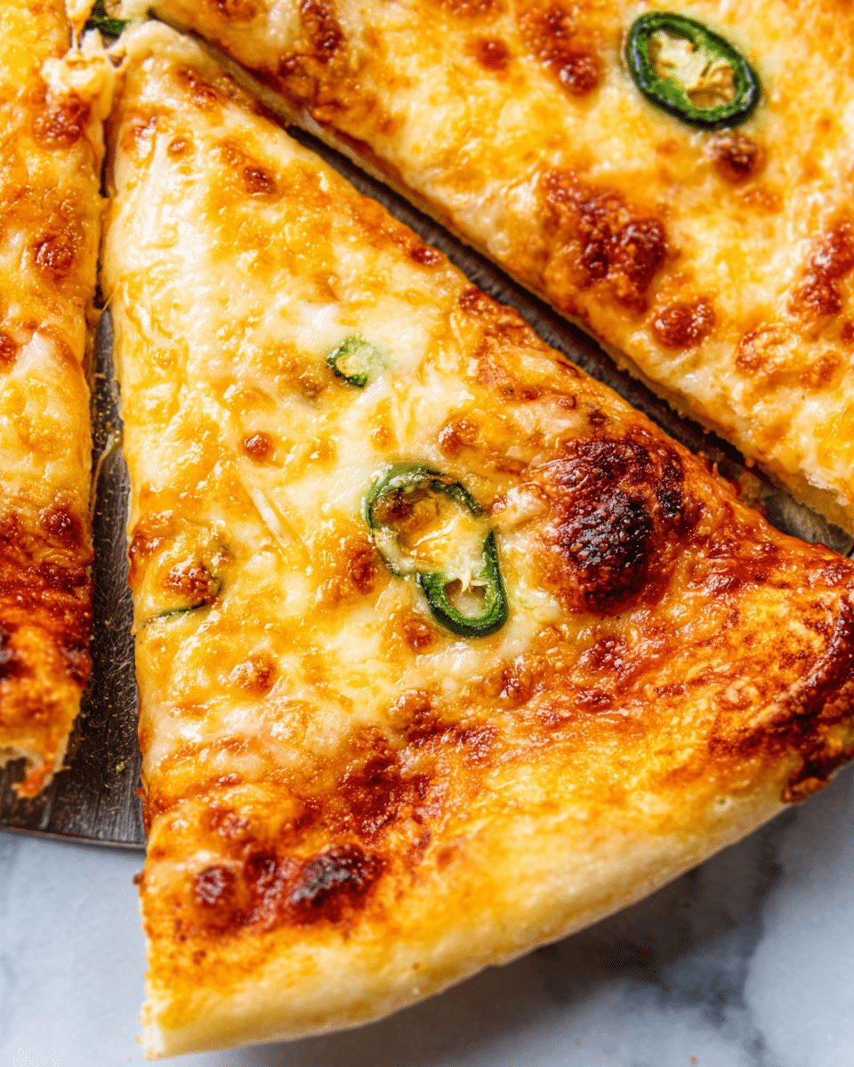 The image shows a close-up of a cheese pizza with several slices visible. Each slice has a golden-brown crust with a slightly raised edge. The pizza is covered with a layer of melted, gooey cheese that is light yellow with toasted brown spots. A simple tomato sauce layer peeks through in some spots underneath the cheese, giving a red contrast. Thin slices of green jalapeño peppers are scattered on top, adding small bursts of green color. The pizza is placed on a metal spatula with a white marbled texture background. Photo taken with an iphone --ar 4:5 --v 7