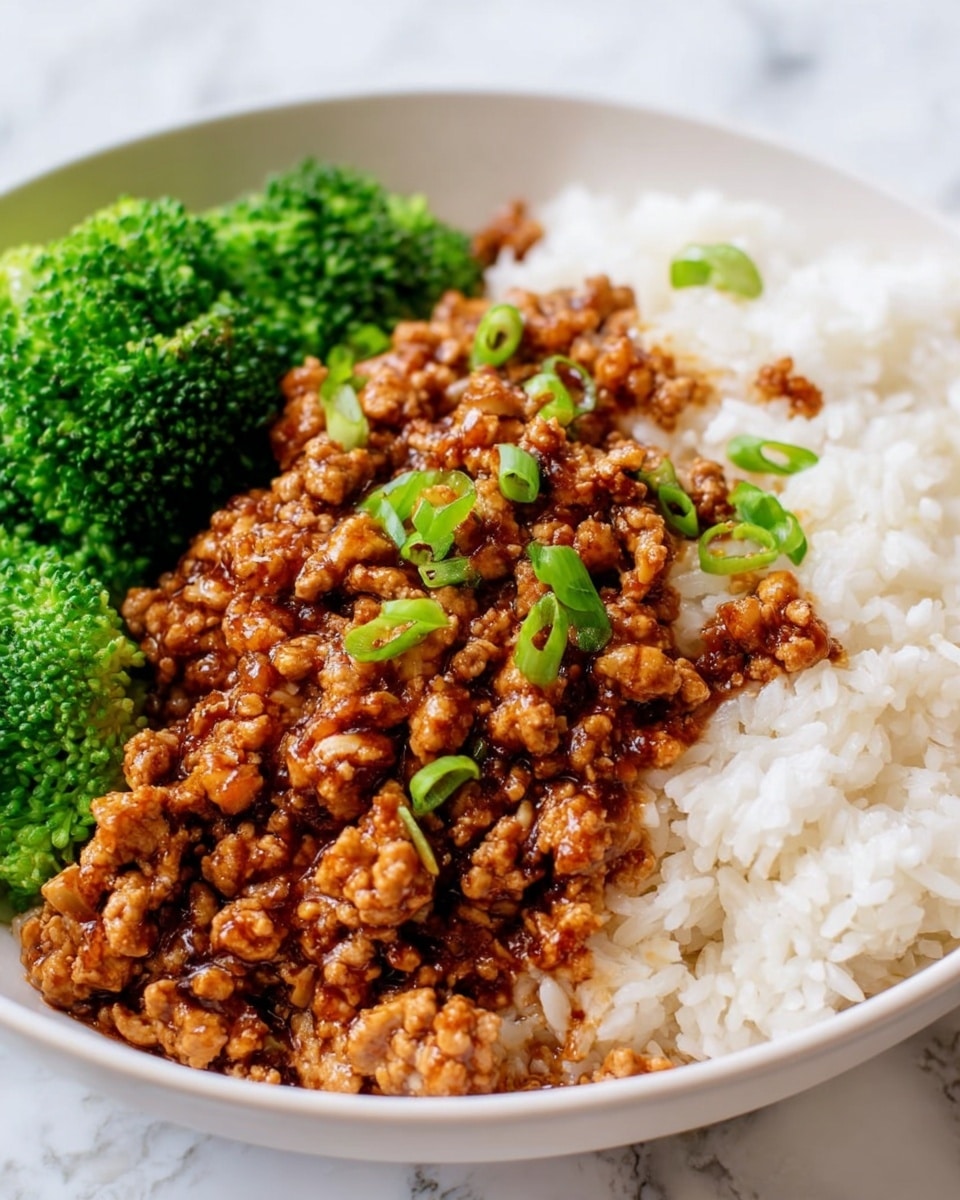 The dish shows three main layers on a white bowl placed on a white marbled surface. On the bottom right, there is a vibrant green broccoli with a textured, leafy surface. Next to the broccoli, a layer of cooked white rice fills half of the bowl, displaying a soft and fluffy texture with separate grains visible. Covering the left half, there is a rich, saucy ground meat mixture that has a shiny, caramelized brown color with bits of green onion sprinkled throughout, adding a fresh touch. The meat is moist and glistening, contrasting nicely with the white rice and green broccoli. photo taken with an iphone --ar 4:5 --v 7