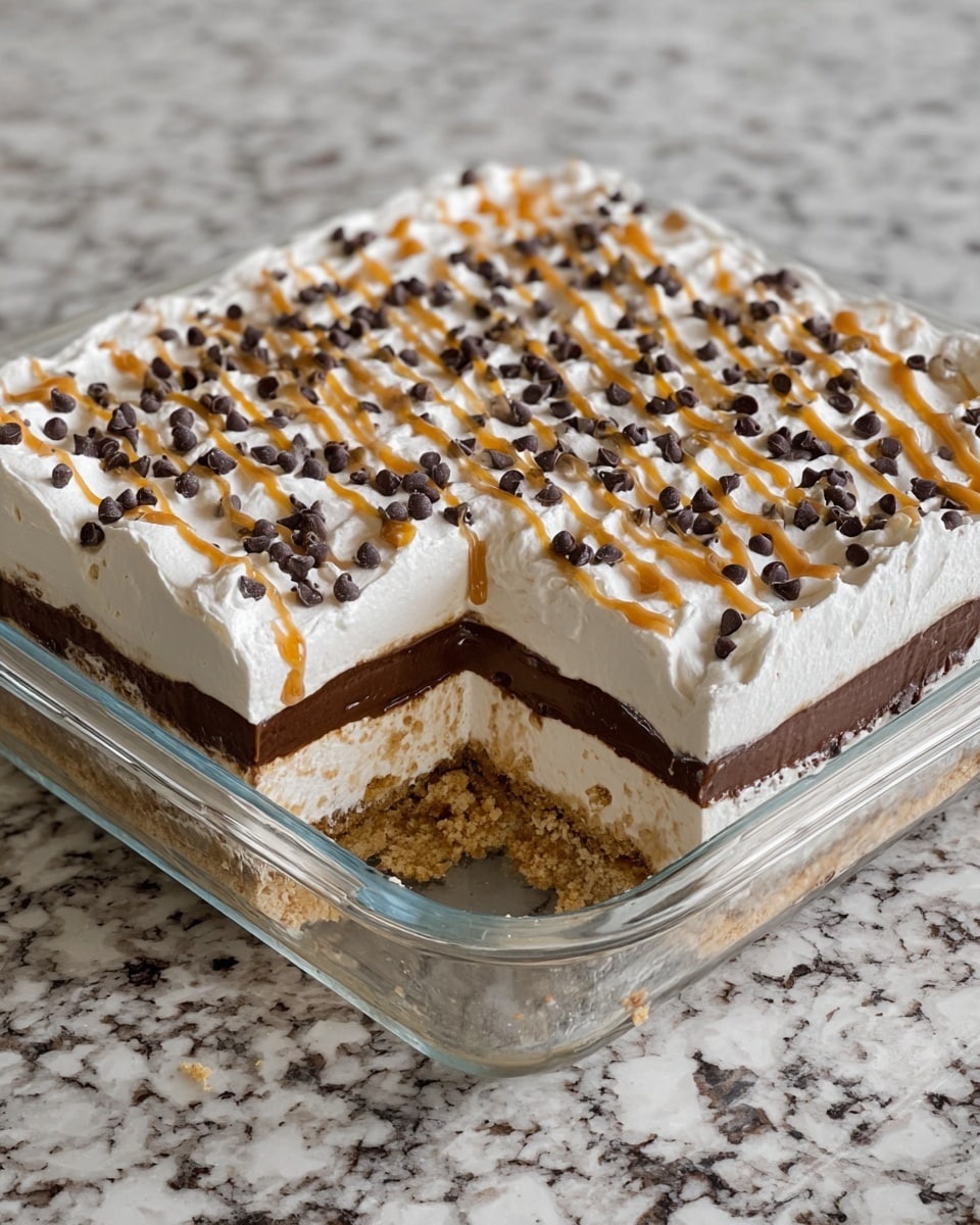 A square glass dish holds a layered dessert with four distinct layers starting from the bottom: a crumbly light brown cookie crust, a smooth white creamy layer, a thick dark chocolate layer in the center, and a fluffy white whipped topping on top. The whipped topping is decorated with small, evenly spaced dark chocolate chips and thin diagonal golden caramel drizzle lines. One corner of the dessert is cut out, showing the clean, clear separation of each layer inside. The dish is placed on a white marbled surface. photo taken with an iphone --ar 4:5 --v 7